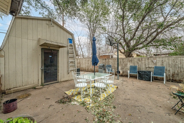 view of patio with outdoor dining space, an outbuilding, and a fenced backyard