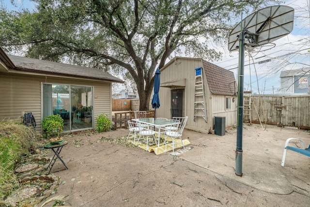 view of patio / terrace featuring an outbuilding, outdoor dining area, and fence