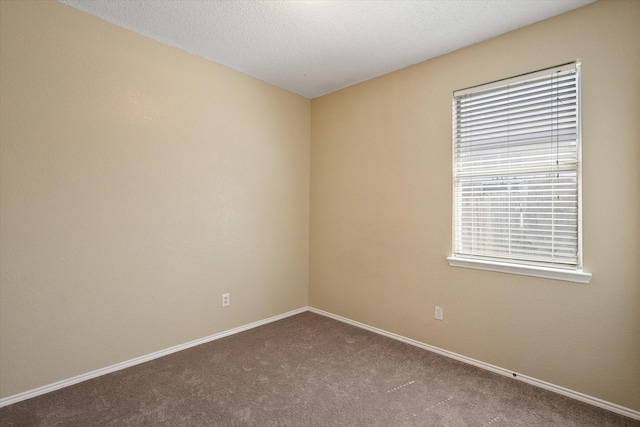 carpeted spare room featuring baseboards and a textured ceiling