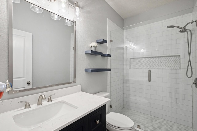 full bathroom featuring a shower stall, toilet, vanity, a textured wall, and a textured ceiling