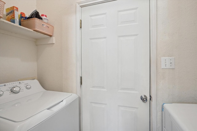 laundry room with laundry area, a textured wall, and washer and clothes dryer