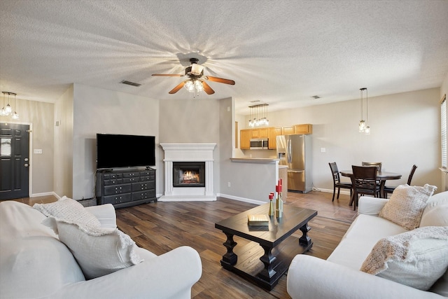 living area with visible vents, a textured ceiling, and wood finished floors