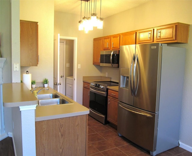 kitchen with a peninsula, dark tile patterned floors, appliances with stainless steel finishes, and a sink