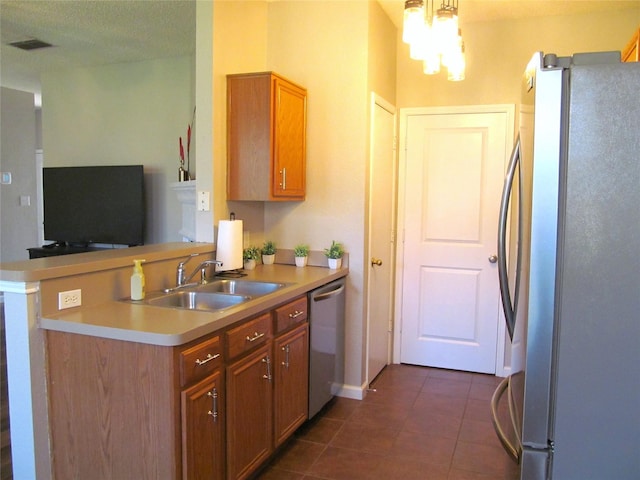 kitchen featuring dark tile patterned floors, light countertops, appliances with stainless steel finishes, a peninsula, and a sink