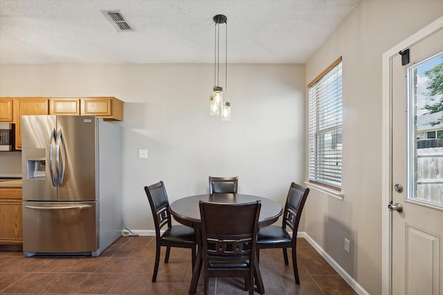 dining room featuring dark tile patterned floors, visible vents, a textured ceiling, and baseboards