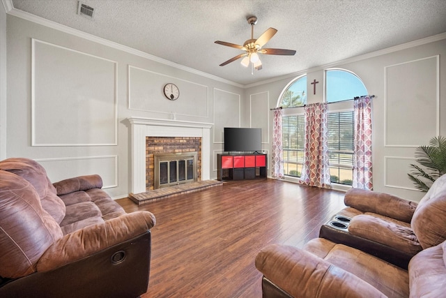 living room with visible vents, wood finished floors, a decorative wall, a fireplace, and crown molding