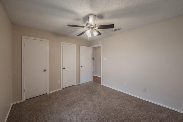 unfurnished bedroom with visible vents, two closets, a textured ceiling, carpet floors, and baseboards