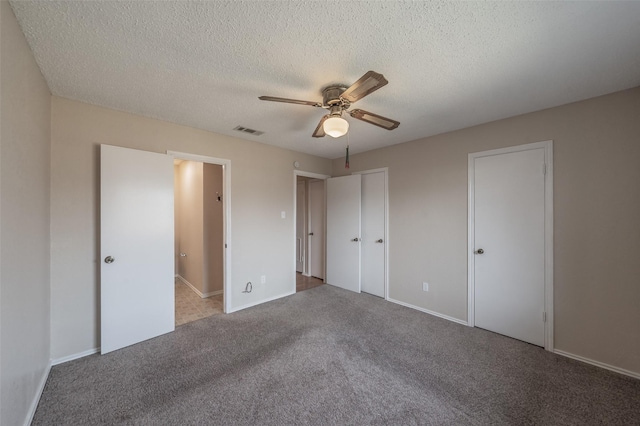 unfurnished bedroom featuring visible vents, two closets, a ceiling fan, a textured ceiling, and carpet