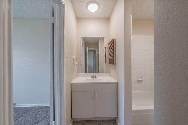 bathroom featuring vanity, tub / shower combination, baseboards, and a textured ceiling