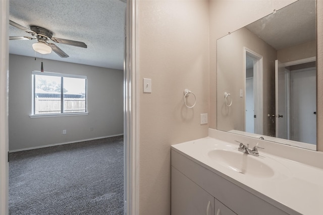 bathroom featuring vanity, ceiling fan, baseboards, and a textured ceiling