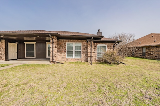 rear view of property featuring a patio area, a lawn, brick siding, and a chimney