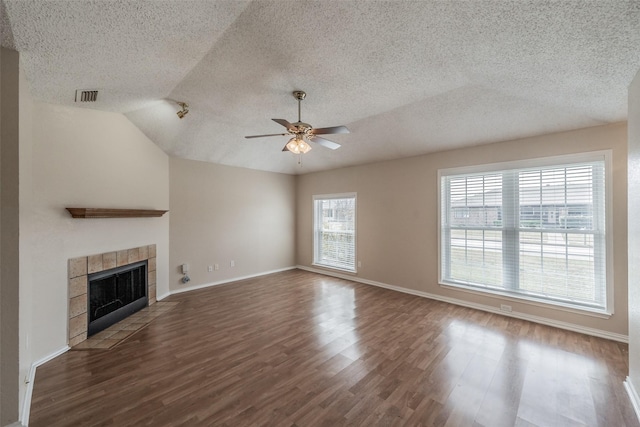 unfurnished living room featuring visible vents, a ceiling fan, a tiled fireplace, wood finished floors, and lofted ceiling