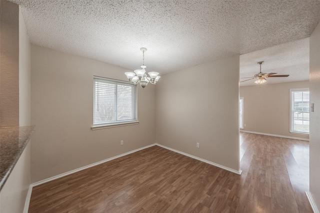 interior space with baseboards, a textured ceiling, wood finished floors, and ceiling fan with notable chandelier