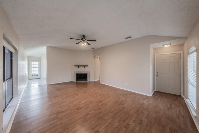 unfurnished living room with wood finished floors, a fireplace, visible vents, and a textured ceiling