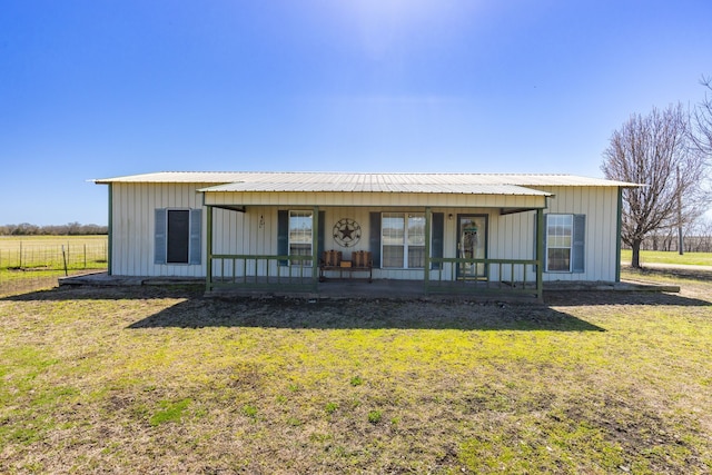 back of property with board and batten siding, a lawn, covered porch, and metal roof