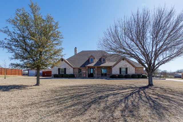 french country home featuring a front lawn, fence, and a chimney