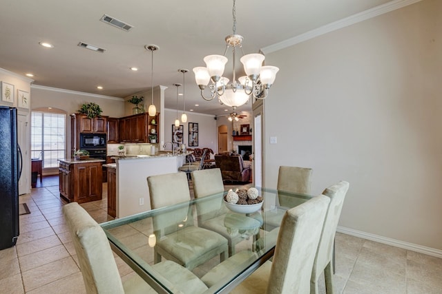 dining room with visible vents, an inviting chandelier, arched walkways, ornamental molding, and a tiled fireplace