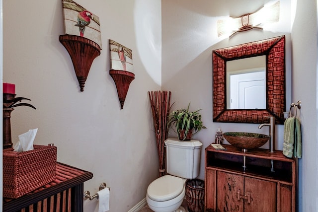 half bath featuring vanity, toilet, and baseboards