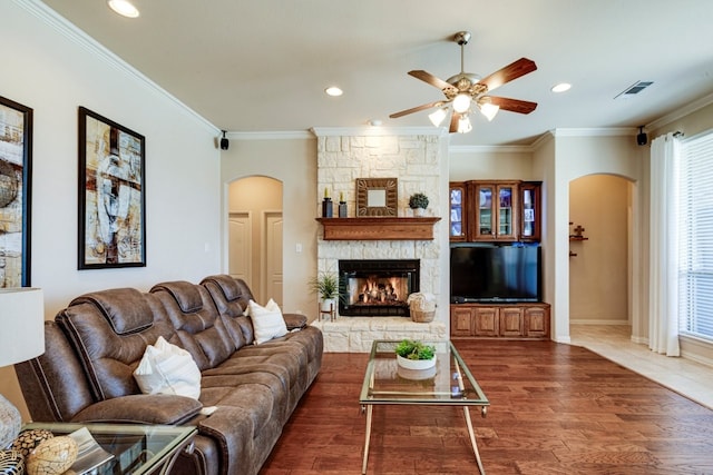 living area with arched walkways, ornamental molding, and a fireplace