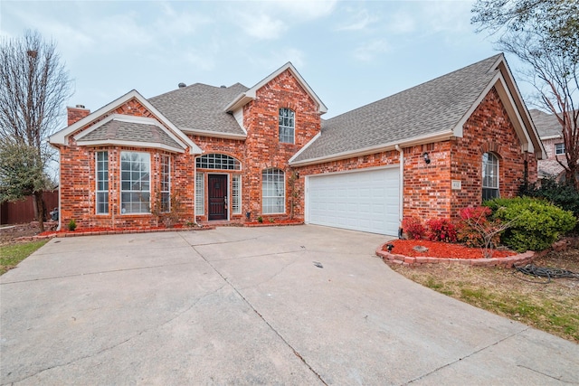 traditional home with roof with shingles, concrete driveway, a garage, brick siding, and a chimney