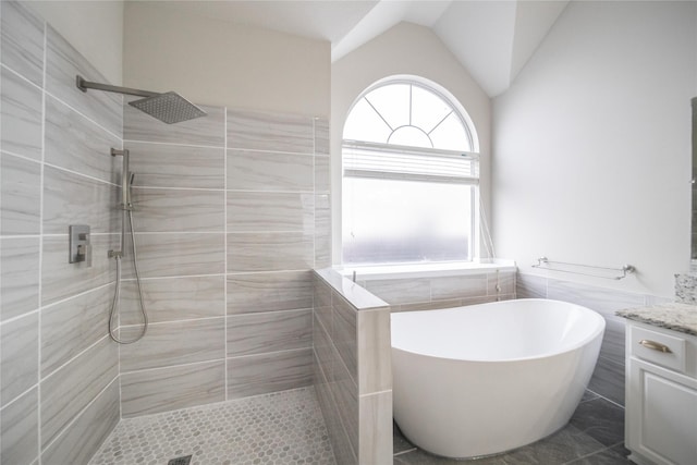 full bath with vanity, a soaking tub, a tile shower, and vaulted ceiling