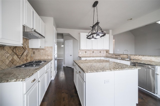 kitchen with a sink, a center island, under cabinet range hood, appliances with stainless steel finishes, and dark wood-style flooring