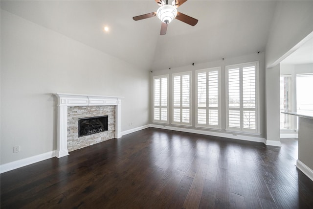 unfurnished living room featuring a stone fireplace, dark wood-type flooring, baseboards, and ceiling fan