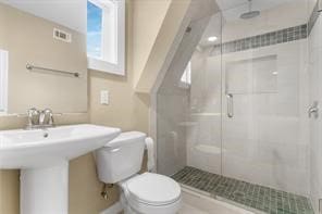 bathroom featuring a sink, toilet, and a stall shower