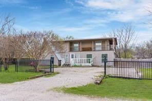 bi-level home featuring a fenced front yard, gravel driveway, and a front lawn