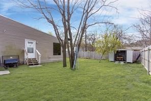 view of yard with entry steps, an outdoor structure, a storage unit, and a fenced backyard