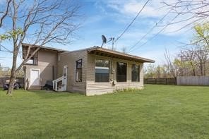 rear view of property featuring a yard and fence