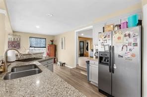 kitchen featuring light stone counters, stainless steel fridge, wood finished floors, and a sink