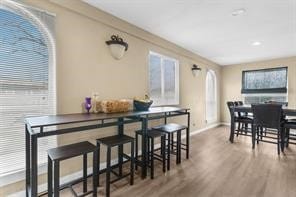 dining area with baseboards, arched walkways, and wood finished floors