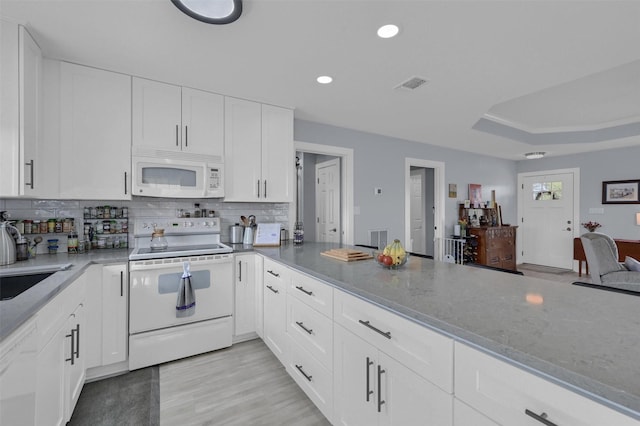 kitchen featuring white appliances, visible vents, white cabinetry, a raised ceiling, and tasteful backsplash