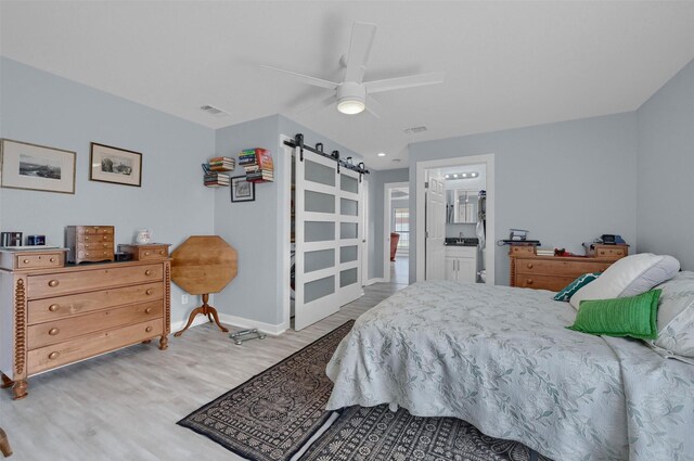 bedroom with visible vents, a ceiling fan, wood finished floors, a barn door, and baseboards