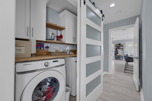 laundry area featuring light wood-style flooring, recessed lighting, cabinet space, washer and dryer, and a barn door