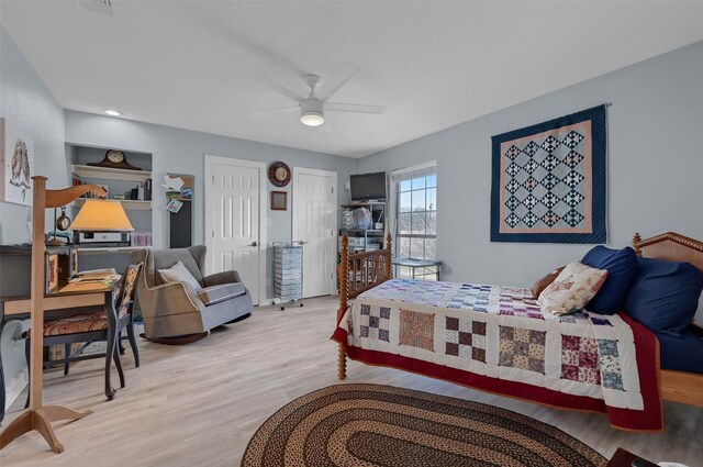 bedroom with wood finished floors, multiple closets, and ceiling fan