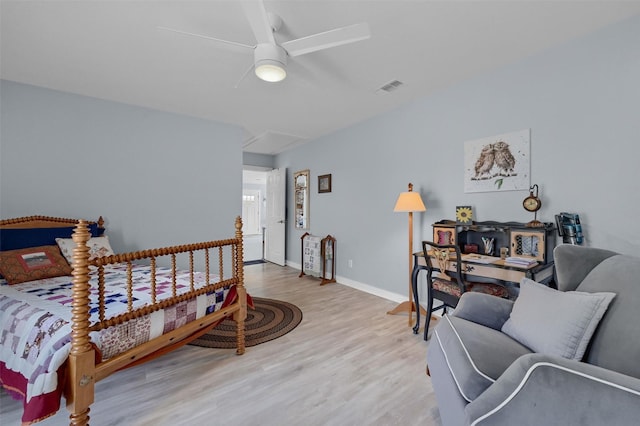 bedroom featuring a ceiling fan, wood finished floors, visible vents, baseboards, and attic access