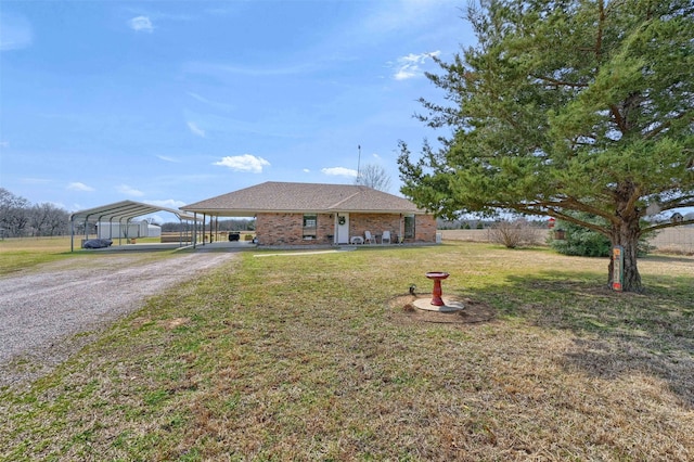 single story home featuring brick siding, driveway, a front lawn, and a carport