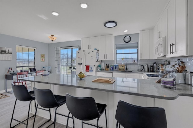 kitchen featuring decorative backsplash, white appliances, white cabinetry, and a sink