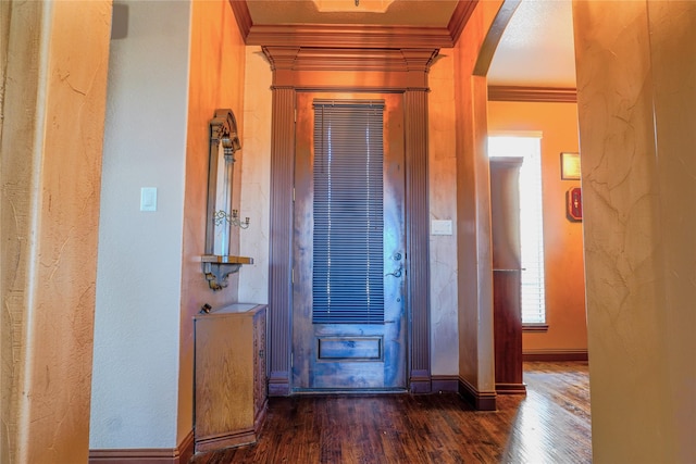 foyer featuring ornamental molding, wood finished floors, arched walkways, baseboards, and a textured wall