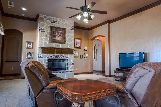 tiled living room featuring baseboards, visible vents, arched walkways, ornamental molding, and a stone fireplace