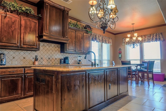 kitchen with ornamental molding, light stone counters, backsplash, light tile patterned flooring, and a chandelier