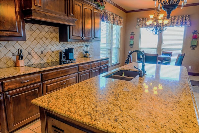 kitchen with light stone counters, custom exhaust hood, ornamental molding, decorative backsplash, and a sink