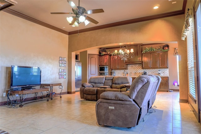 living area featuring crown molding, a high ceiling, ceiling fan with notable chandelier, and baseboards