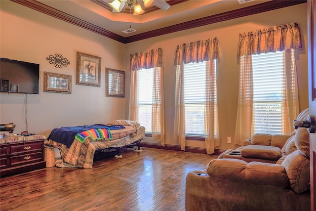 bedroom with visible vents, crown molding, a tray ceiling, and wood finished floors