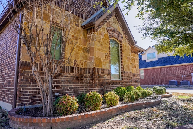 view of home's exterior featuring cooling unit, stone siding, and brick siding