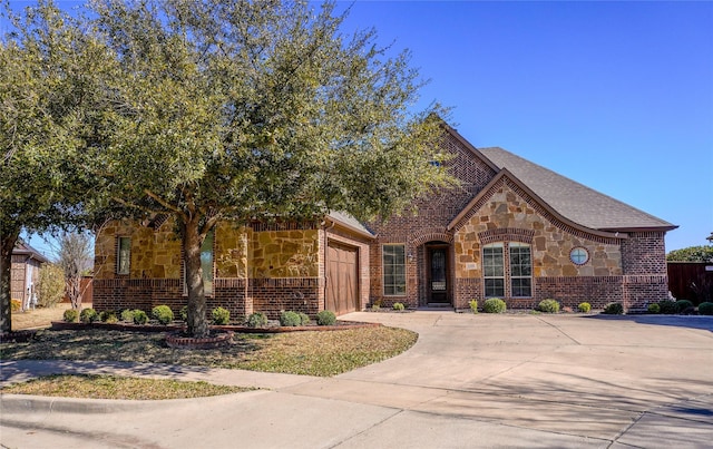 view of front of property with a shingled roof, concrete driveway, a garage, stone siding, and brick siding