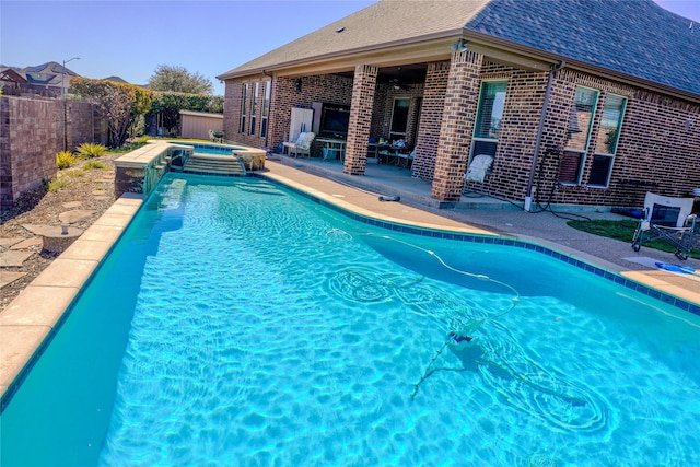 view of swimming pool featuring a pool with connected hot tub, a patio area, and a fenced backyard