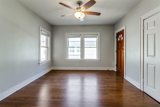 empty room with dark wood finished floors, a healthy amount of sunlight, and baseboards